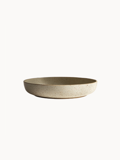 A shallow, round ceramic bowl with a speckled beige and light grey texture, on a plain white background.