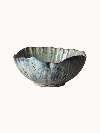 A rustic ceramic bowl with a mottled light blue and beige glaze with brown speckled details, on a plain white background.